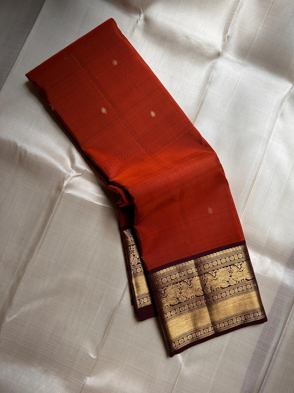 Rust Annam Butta — Kanchipuram Pure Silk

Rust-orange (semman/rust) body with zari chakram buttas

Deep maroon korvai borders with annam (swan) vine motifs

Lavish maroon-gold zari pallu with temple serrations

Silk Mark Certified | Free Shipping