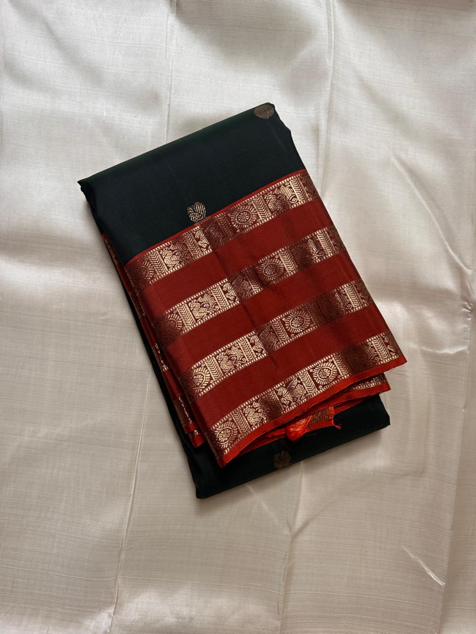 Pachai Mayil Chakram Varisaipet — Pure Kanchipuram Silk Saree
Deep pachai (bottle green) body with antique-gold chakram buttas, rust-vermillion varisaipet borders, and a radiant kesari-orange zari pallu.
Silk Mark Certified • Blouse Stitching Available