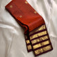 Ember Yazhi – Pure Kanchipuram Silk Saree
Burnt Orange Body with Vaira Oosi Stripes & Yazhi Buttas
Contrast Maroon Varisaipet Border with Gold Zari Panels
Grand Maroon Brocade Pallu with Intricate Motifs

Silk Mark Certified, delivery in 2 weeks