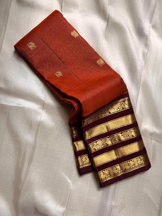 Ember Yazhi – Pure Kanchipuram Silk Saree
Burnt Orange Body with Vaira Oosi Stripes & Yazhi Buttas
Contrast Maroon Varisaipet Border with Gold Zari Panels
Grand Maroon Brocade Pallu with Intricate Motifs

Silk Mark Certified, delivery in 2 weeks