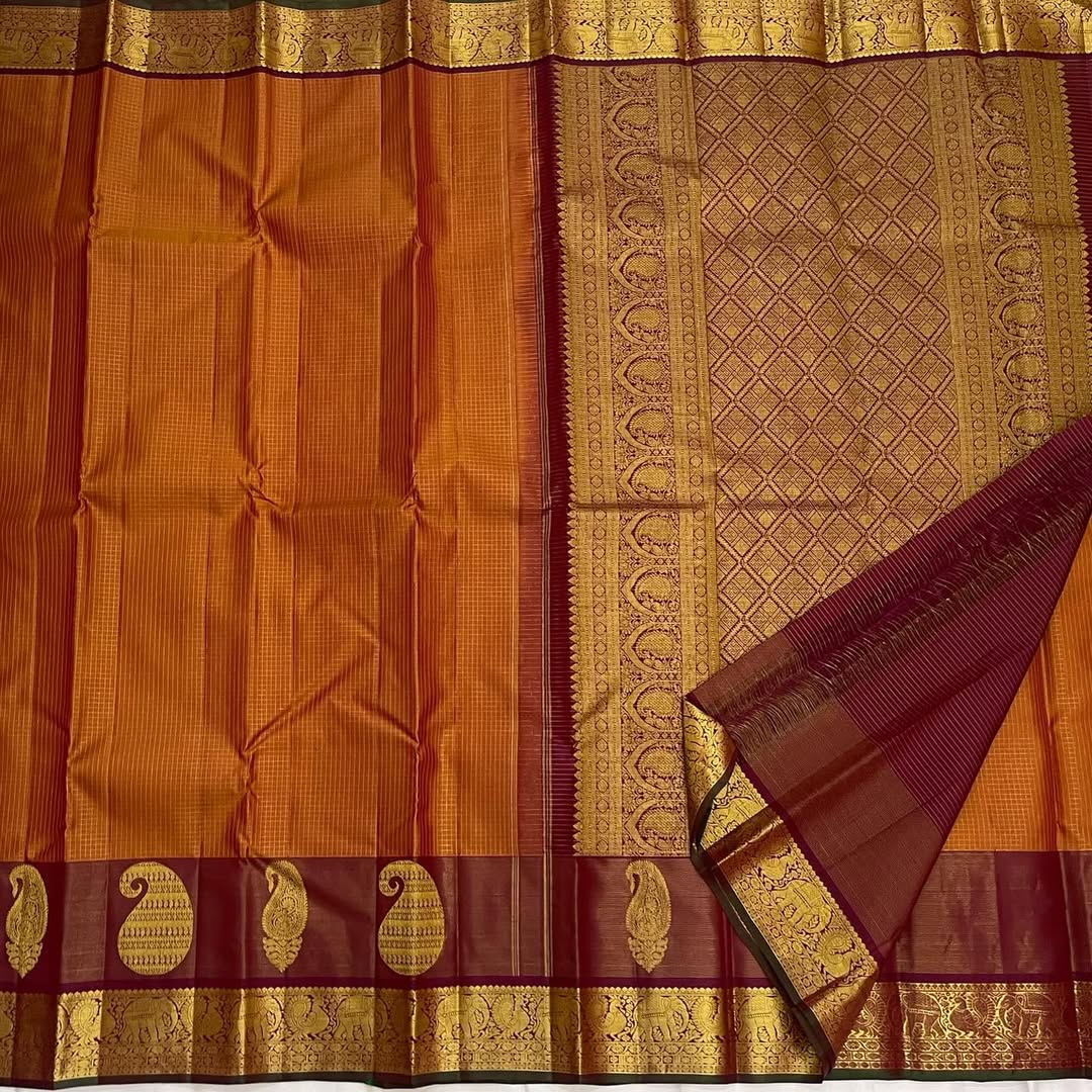 Ushas — Rust Orange Pure Kanchipuram Silk Saree
Radiant Rust Orange Oosi Kattam body with ornate Paisley 2gm Zari ✨
Arakku Red Vanasringaram, Muthuseer & Kamalam border with Fishpettu 
Exquisite Arakku Red diamond-pet grid Zari pallu green selvedge