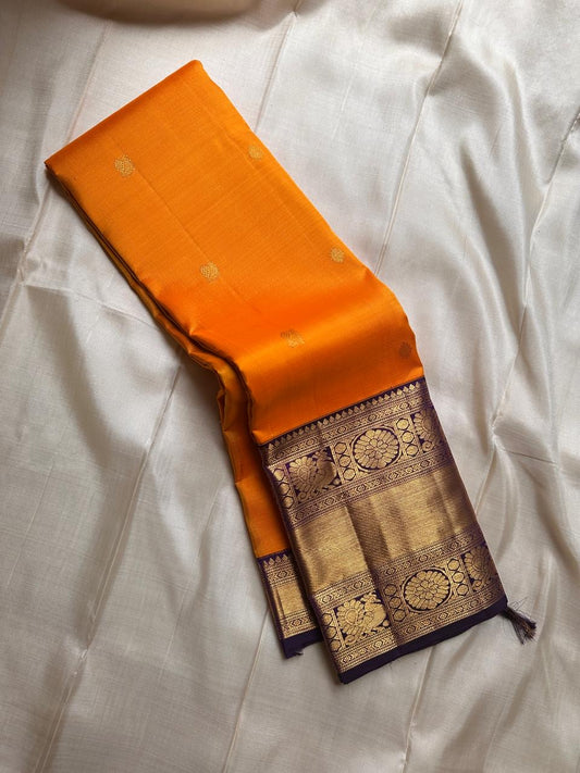 This Maambazha yellow Kanchipuram silk saree features zari mayil buttas and a deep blue rettapet border with kamalam motifs — a timeless blend of tradition and grace.