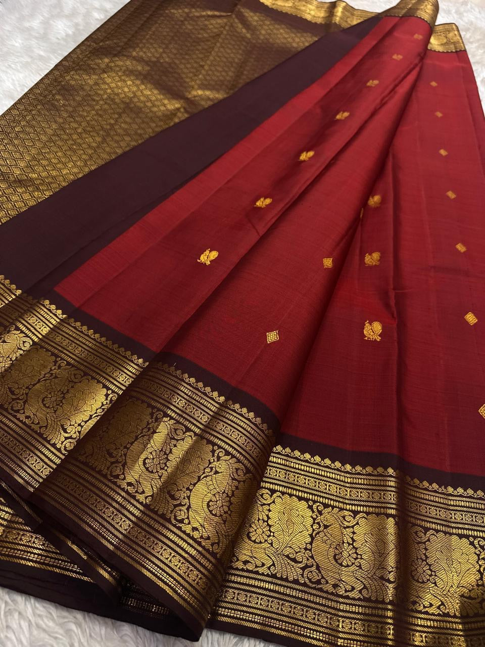 Sienna Red Mayuri Butta — Pure Kanchipuram Silk
Sienna-red body with zari mayuri buttas & antique gold border
Contrast coffee-brown pallu in rich zari jaal • Silk Mark Certified • Free USA Shipping