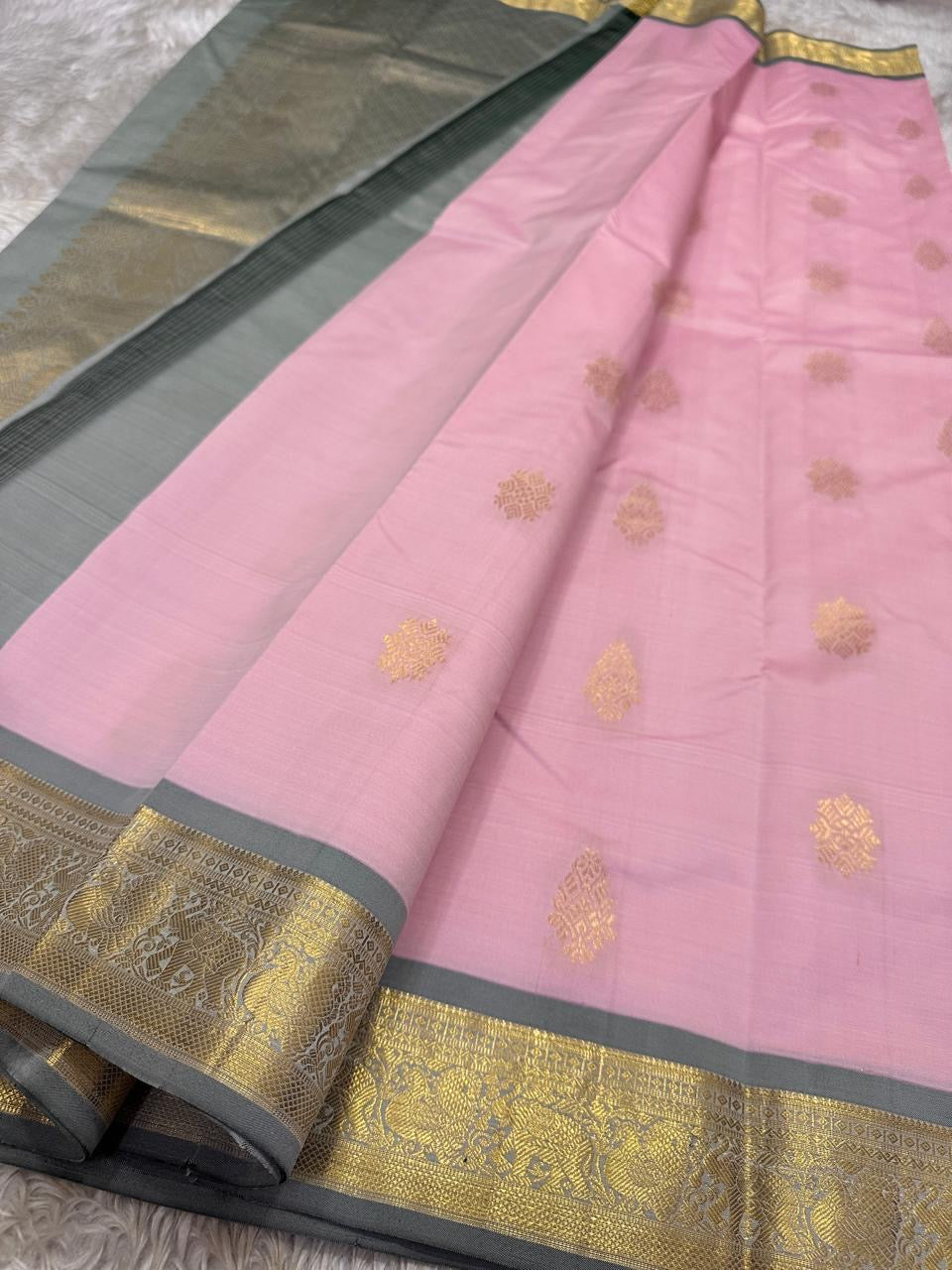 Blush Ash Mayil – Pure Korvai Kanchipuram Silk Saree
Soft blush-pink body with gold zari paisley buttas for a delicate look
Contrast ash-grey border with peacock & floral vine motifs in zari
Grand ash-grey brocade pallu with intricate … chk description