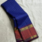 Indra Neelam Kattam – Pure Kanchipuram Silk Saree
Royal Blue Body with Fine Zari Grid Checks
Copper-Rose Korvai Borders with Floral & Chevron Zari
Grand Purple Pallu with Tassels
Silk Mark Certified | ships in 2  weeks | Blouse Stitching Available
