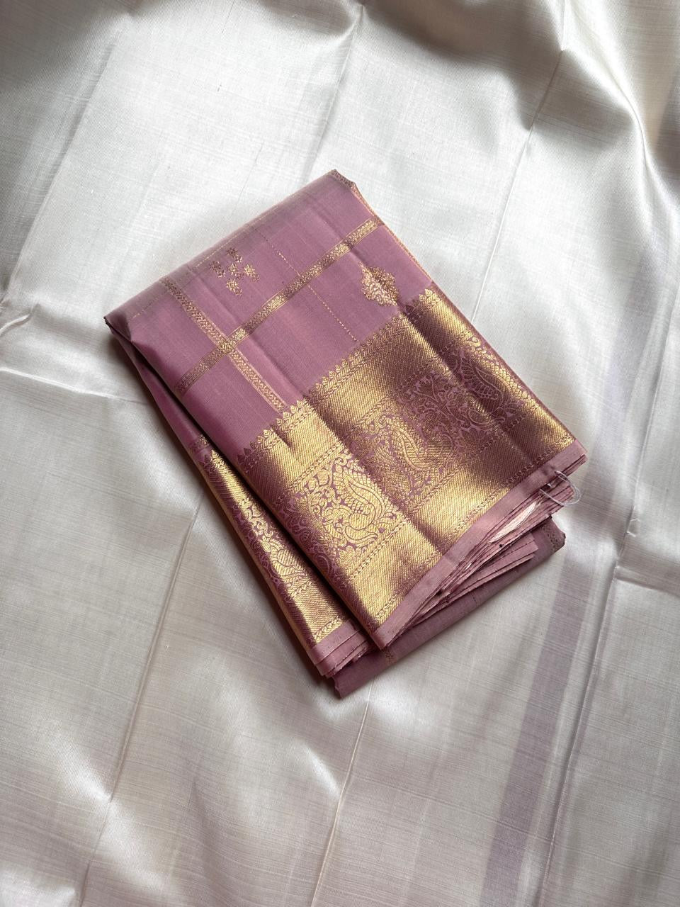 Lilac Mayil – Pure Kanchipuram Silk Saree
Ash-Lilac Body with Zari Kattam Checks & Buttas
Broad Antique-Gold Peacock Zari Borders
Grand zari Pallu 
Silk Mark Certified | Fall & Pico Done | Blouse Stitching Available | ships in two weeks Free