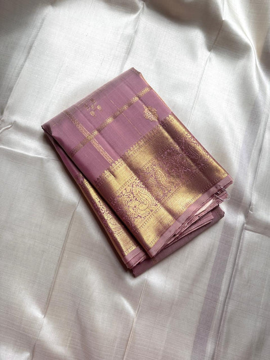 Lilac Mayil – Pure Kanchipuram Silk Saree
Ash-Lilac Body with Zari Kattam Checks & Buttas
Broad Antique-Gold Peacock Zari Borders
Grand zari Pallu 
Silk Mark Certified | Fall & Pico Done | Blouse Stitching Available | ships in two weeks Free