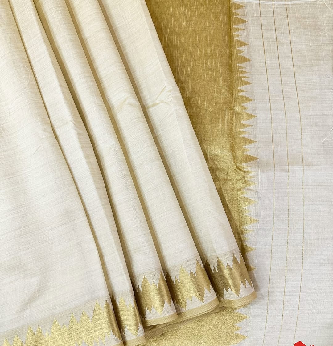 Minimal yet majestic, this ivory-beige silk saree is a celebration of simplicity and sophistication. The body is plain and luminous,  texture of the silk shines through. golden zari border with a sharp, zigzag temple-inspired pattern - perfect for Onam