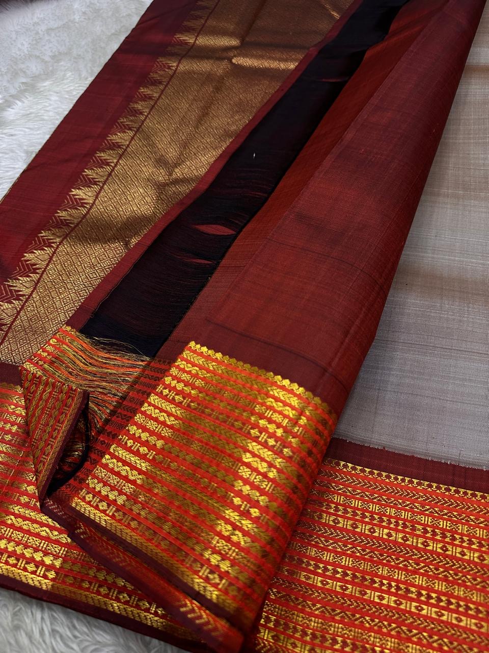 Taupe Glow – Pure Kanchipuram Silk Saree
Ash Taupe Grey Body with Lilac Undertone
Intricate Devadatta Flying Horse Motif in Zari
Deep Maroon Varisaipet Border with Rich Contrast
Grand Zari Pallu with Thazampoo Temple Motifs