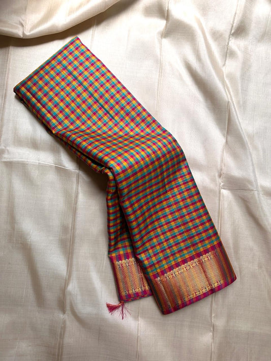 A classic Kanchipuram in Pattani Kattam checks with green, magenta, mustard, and cream.
Finished with a contrast pink border and pallu.
Paisley and chakram motifs in a graceful grid add timeless charm.