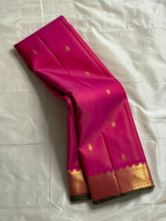 Rani Vairaoosi – Pure Kanchipuram Silk 💗

Fine Pinstriped Weave with Gold Buttas ✨

Antique-Gold Zari Border & Green Selvedge 🌿

Grand Zari Brocade Pallu with Medallion Checks 🪔

Silk Mark Certified • Ships in Two Weeks • Free USA Shipping