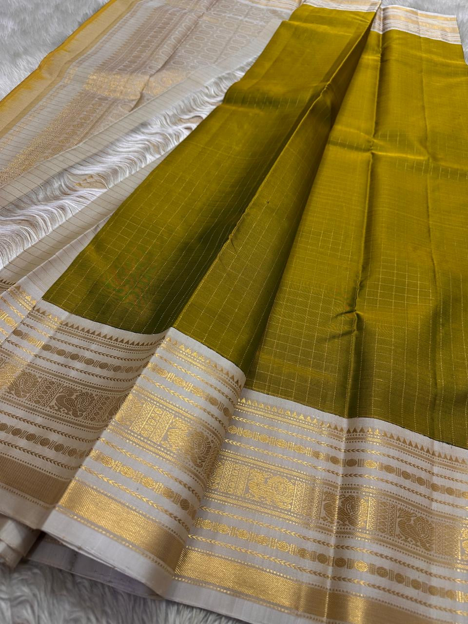 Luminous Lemon-Olive Green — White Korvai Kanchipuram

Pure Silk | Vairaoosi Checks | Korvai Contrast Borders

Classic White & Gold Pallu with Coin Jaal Motifs

Perfect for Muhurtham, Haldi & Temple Occasions

Silk Mark Certified | Free Shipping | Shi