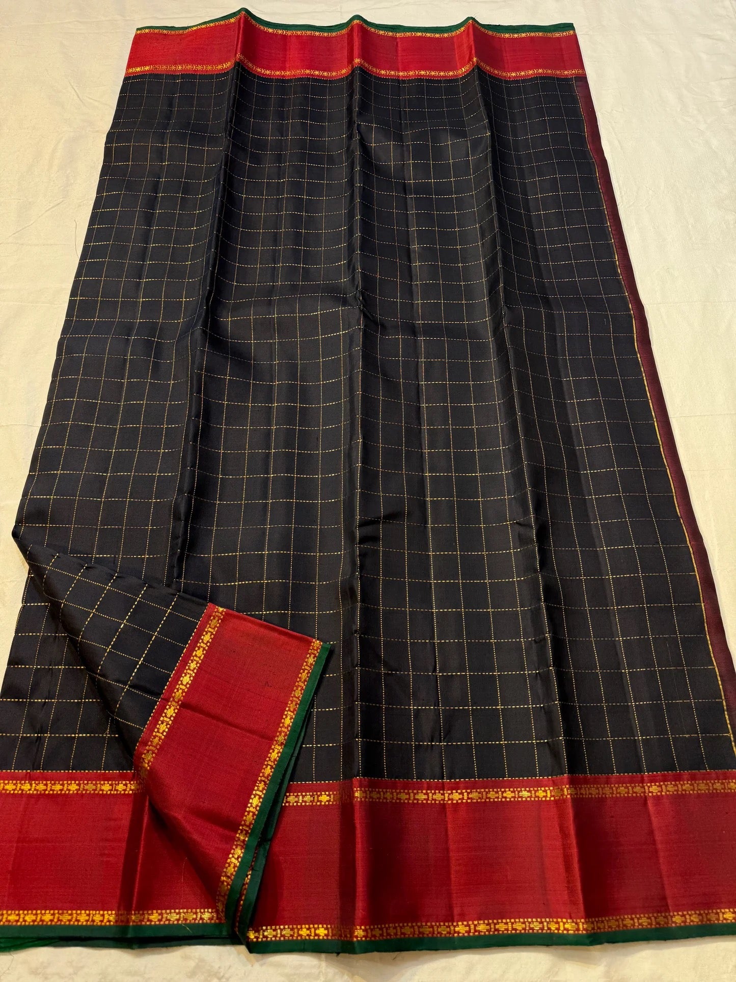 Deep red Varisaipet border with gold zari stripe and green accent on black Kanchipuram silk saree