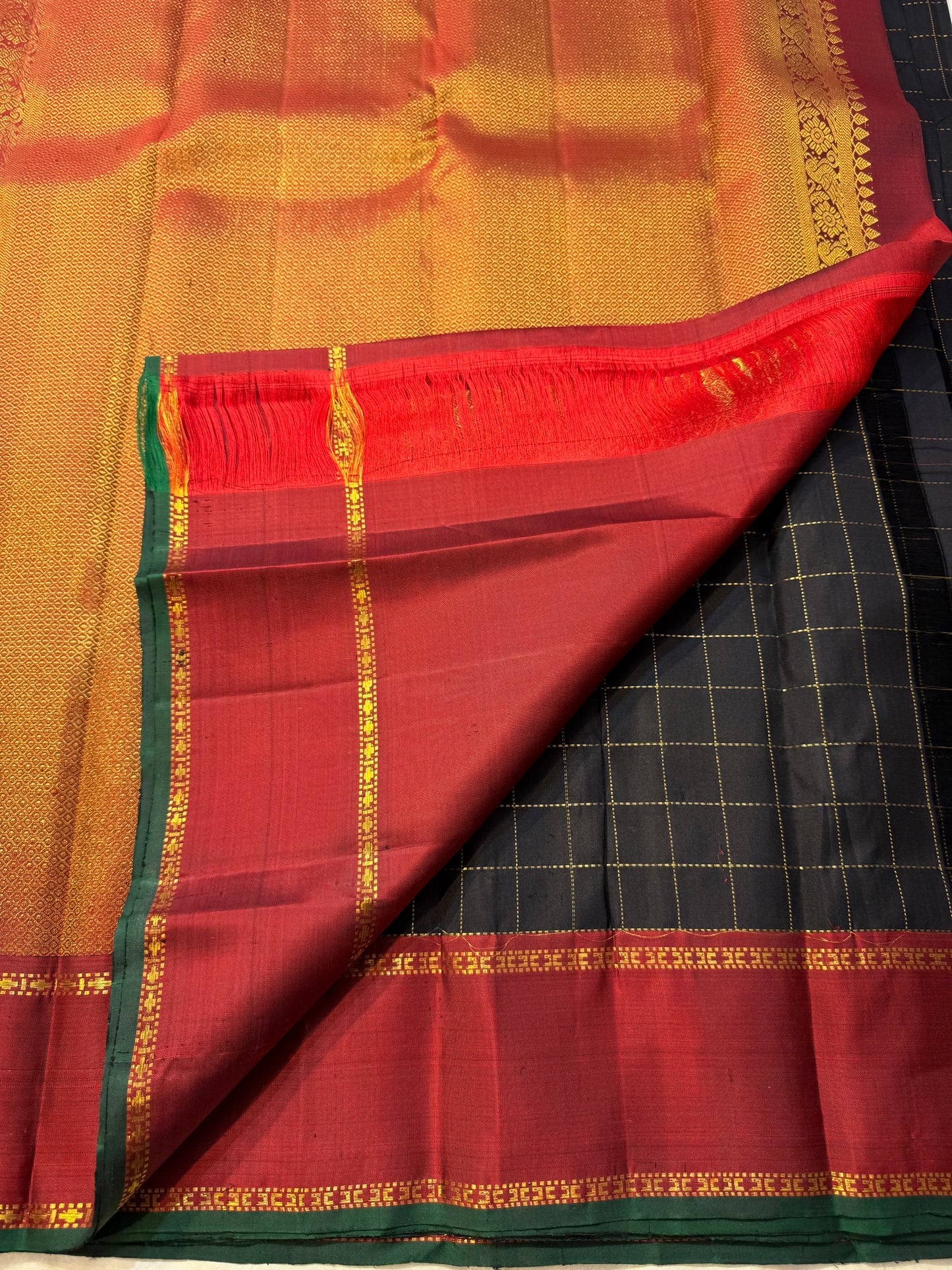 Jet black Kanchipuram saree body with luminous gold zari grid — close-up