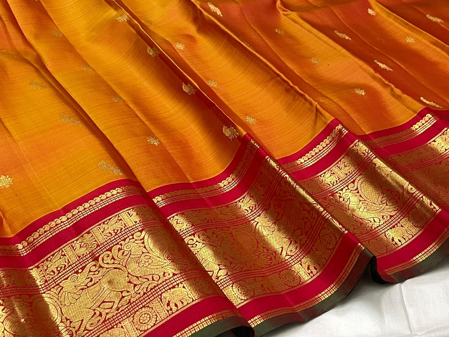 Close-up of burnt orange mulberry silk body with gold zari Mayil butta and Kamalam butta