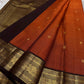 Kavi — oosi  kattam Pure Kanchipuram Silk Saree

Burnt Orange (saffron–rust) body
Deep coffee-maroon contrast border with grand antique-gold zari
Rich brocade pallu; peacock & floral vines in the border
Silk Mark Certified