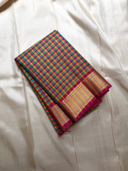 A classic Kanchipuram in Pattani Kattam checks with green, magenta, mustard, and cream.
Finished with a contrast pink border and pallu.
Paisley and chakram motifs in a graceful grid add timeless charm.