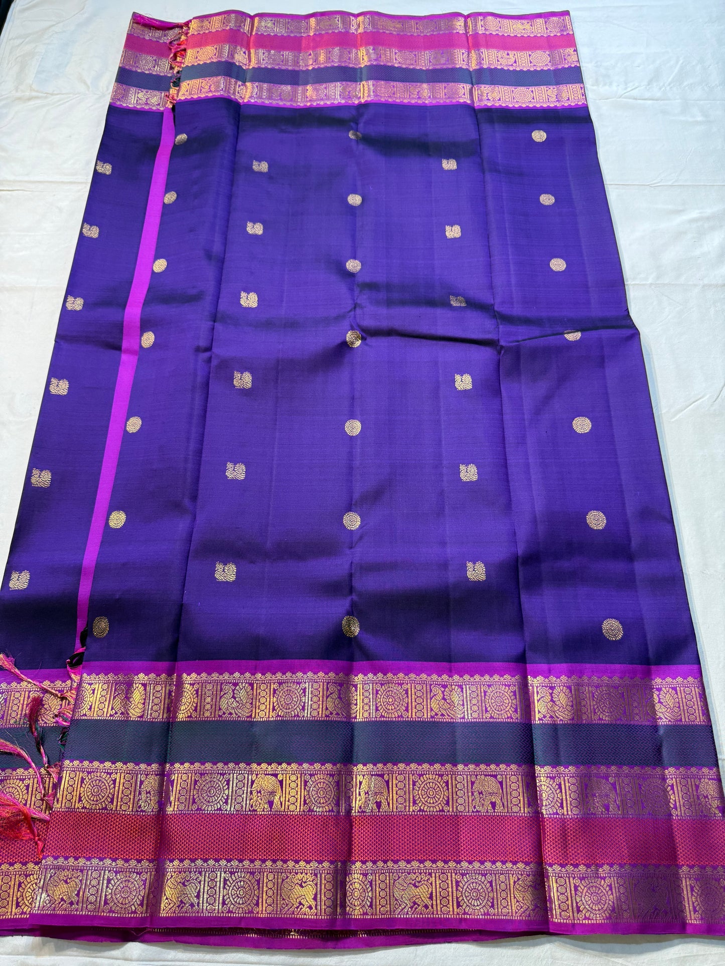 Peacock Purple Rajam – Pure Silk Kanchipuram Saree
Deep Peacock Purple Body with Gold Zari Buttas
Korvai Borders with Temple, Peacock & Elephant Motifs
Rich Zari Pallu with Vertical Brocade Stripes
Silk Mark Certified | ships in two week| Blouse Stitching