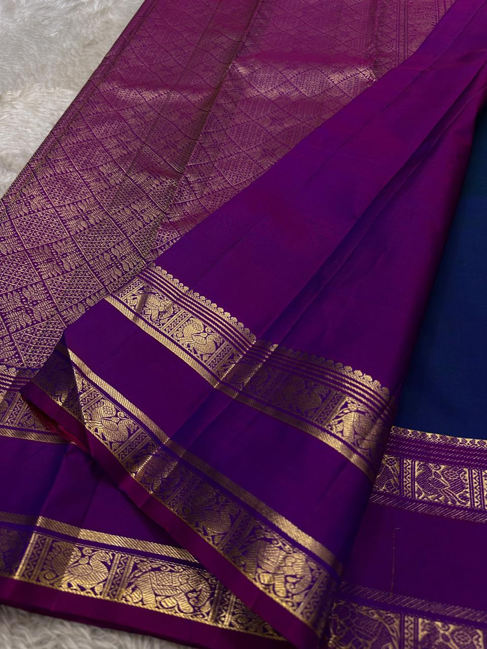 Purple Allure – Pure Kanchipuram Silk Saree
Peacock-blue body adorned with petite zari floral buttas 🌸
Contrast royal-purple border with grand elephant procession 🐘
Rich zari brocade pallu in floral motifs ✨

Silk Mark Certified, delivery in 2 weeks