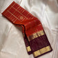 Cinnamon Kattam – Pure Kanchipuram Silk Saree
Vermillion red body with gold kattam checks & floral  buttas
Contrast plum purple korvai borders with rich zari weave
Grand zari pallu with lattice & floral motifs in gold
Silk Mark Certified ships in 2weeks