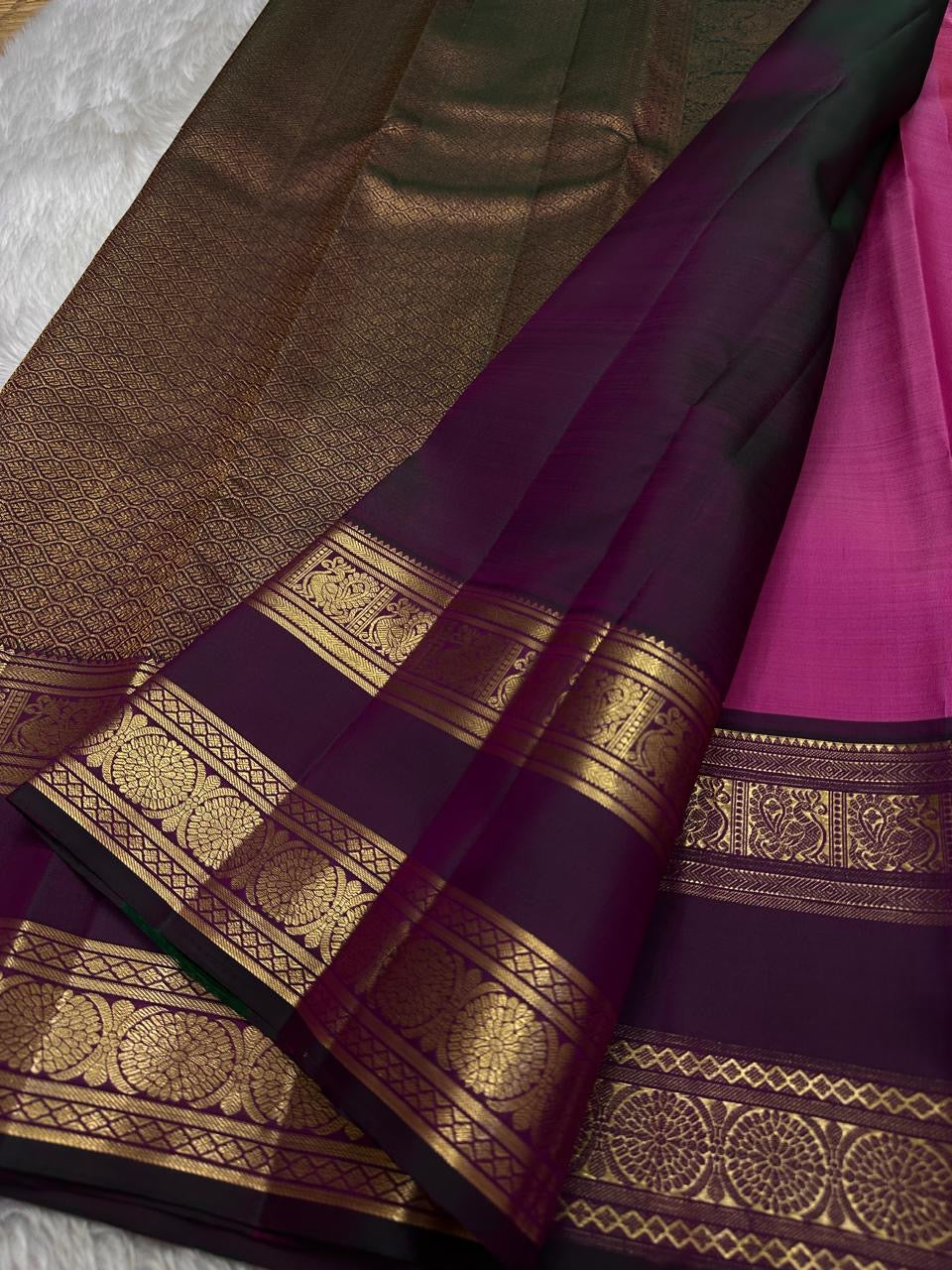 Anvitha – Magenta & Pink Shot Kanchipuram Pure Silk Saree
Glowing dual-tone silk body in radiant magenta and pink
Paired with a rich brown rettapet border featuring peacocks & floral vines in gold zari