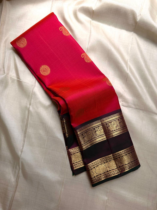 Revathi – Maroon and Vermilion Kanchipuram Pure Silk Saree with Gold Zari Border
Bold pure silk Kanchipuram saree, featuring a deep red shot maroon body with a vibrant vermilion upper half. Rich rettapetu border with mayil chakram motifs