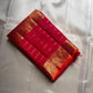 Folded pink-red Kanchipuram silk saree with gold zari lines and rich elephant border on an ivory silk background.