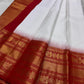 A true festival essential white with dashing red pure silk Kanchipuram saree with a kamalam and mayil detailed border zari work , red reku and Pallu