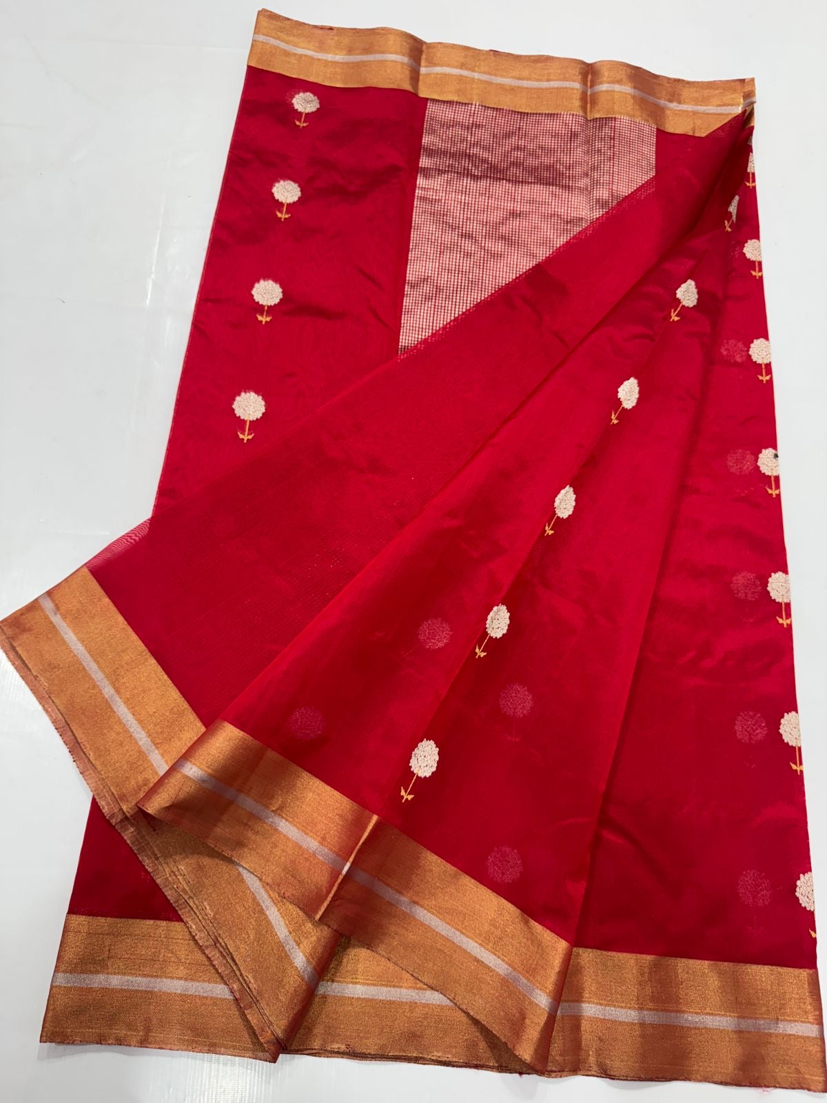 Roja Pushpam — Pure Silk Chanderi (Crimson Blossom)
Crimson red body with silver-ivory floral buttas & gold stems 🌸
Antique copper-gold border • Red-gold tissue pallu • Silk Mark Certified • Free Shipping within USA • Ships in Two Weeks