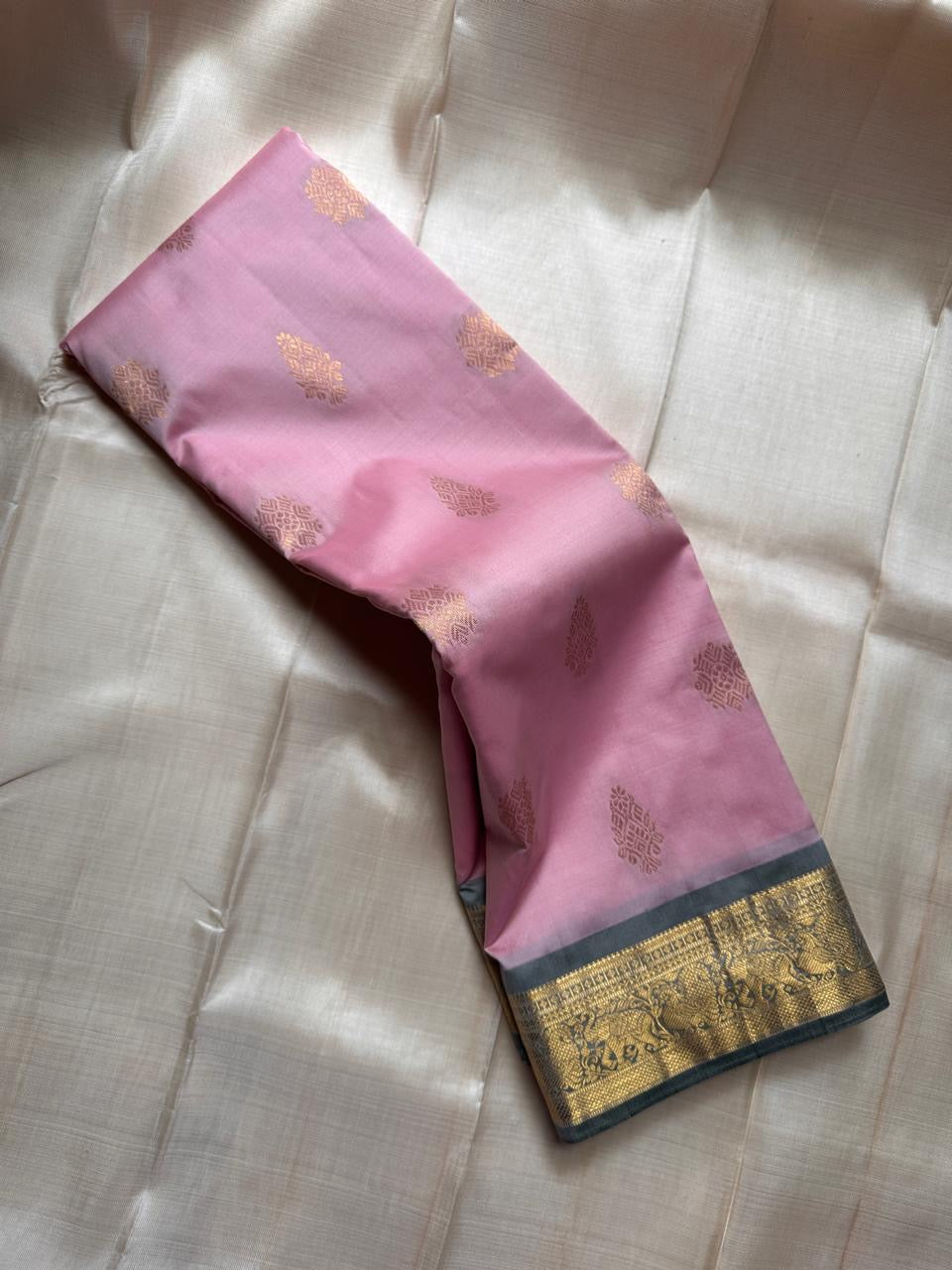 Blush Ash Mayil – Pure Korvai Kanchipuram Silk Saree
Soft blush-pink body with gold zari paisley buttas for a delicate look
Contrast ash-grey border with peacock & floral vine motifs in zari
Grand ash-grey brocade pallu with intricate … chk description