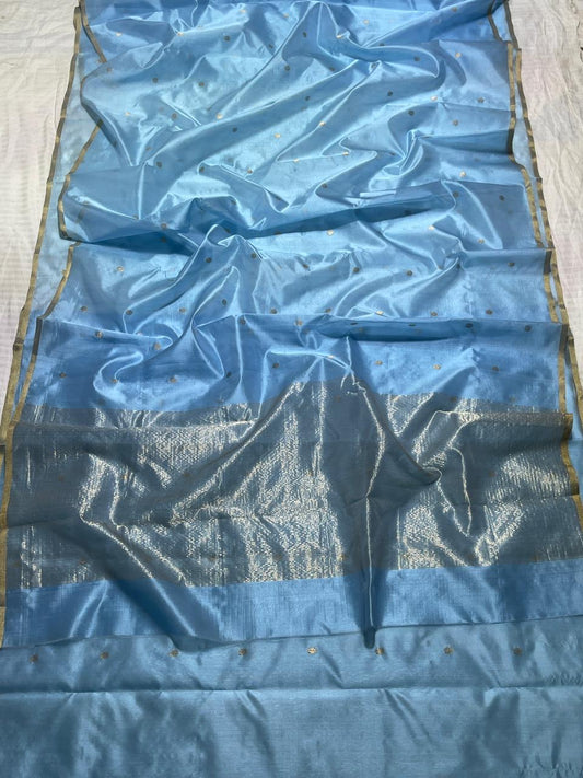 Blue elegance meets timeless craftsmanship in this Chanderi silk saree, delicately woven with a soft sheen and a feather-light drape. The saree features small gold zari buttas scattered across the body, lending it a graceful sparkle!