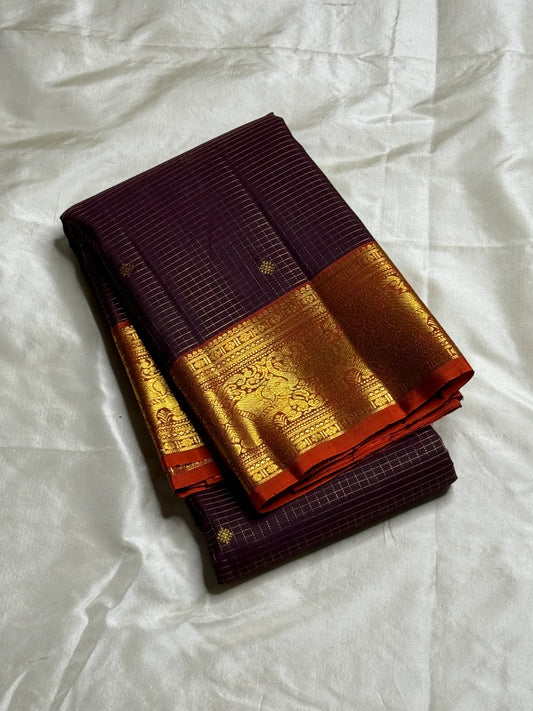 Deep Plum Orange
A regal dance of plum and burnt orange
Micro-checks kissed with golden buttas
Elephant borders marching in heritage grandeur
Brocade pallu glowing in timeless zari brilliance

Silk Mark Certified, delivery in 2 weeks