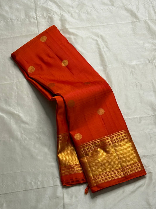 Maya
Vibrant Orange Kanchipuram Silk Saree with Lustrous Gold Coin Buttas
Handwoven Traditional Rudhraksham Seer and Intricate Arai Maadam Zari Border
Richly Crafted Pallu Featuring Elegant Gold Zari Panels for a Regal Finish