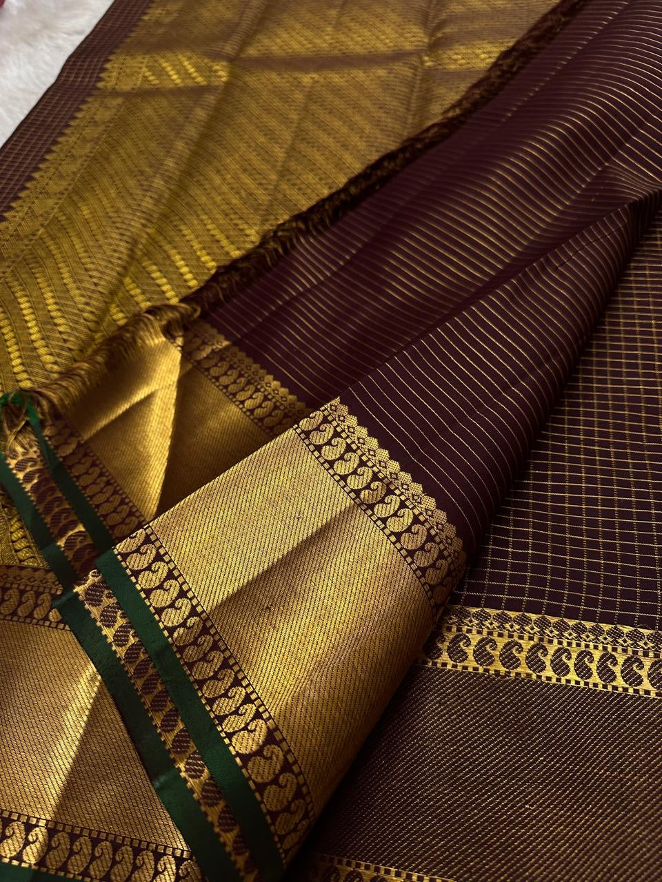 closeup of wide gold zari woven border with green edge on pure kanchipuram silk saree