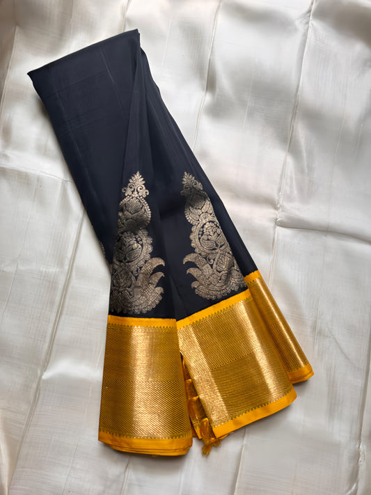 A striking black silk saree adorned with rich gold-yellow zari work, exuding timeless elegance and regal charm.