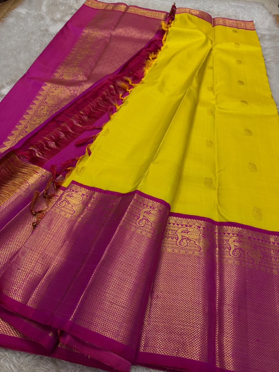 Crafted from pure Kanchipuram silk, this golden yellow saree features a broad pink border with traditional Yali motifs. The pallu is richly woven with bold elephant designs in thick zari—an elegant blend of heritage and grandeur.
