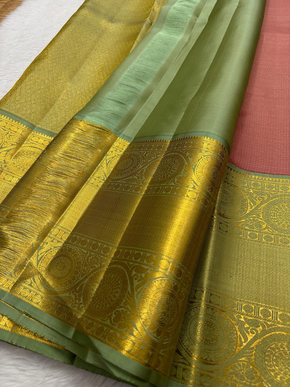 Vahini – Pleasant Peach Pink Pure Kanchipuram Silk Saree with Zari Kattam Checks, Silver & Gold Peacock Buttas, Sage Green Border Adorned with Kamalam Vines and Baavanji Motifs, and an Ornate Zari Pallu with Majestic Peacocks