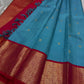 Full drape view of sky blue saree with red zari border, gold pallu and tassels