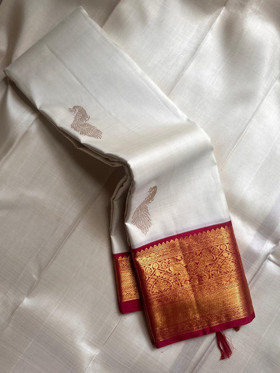 Ivory Mayil – White Mayil Butta Korvai Kanchipuram Silk Saree
Pure handloom silk | Ivory body with gold peacock buttas
Wine-maroon korvai border with peacock & floral zari motifs
Grand gold-zari brocade pallu | ships in two weeks
Silk Mark Certi