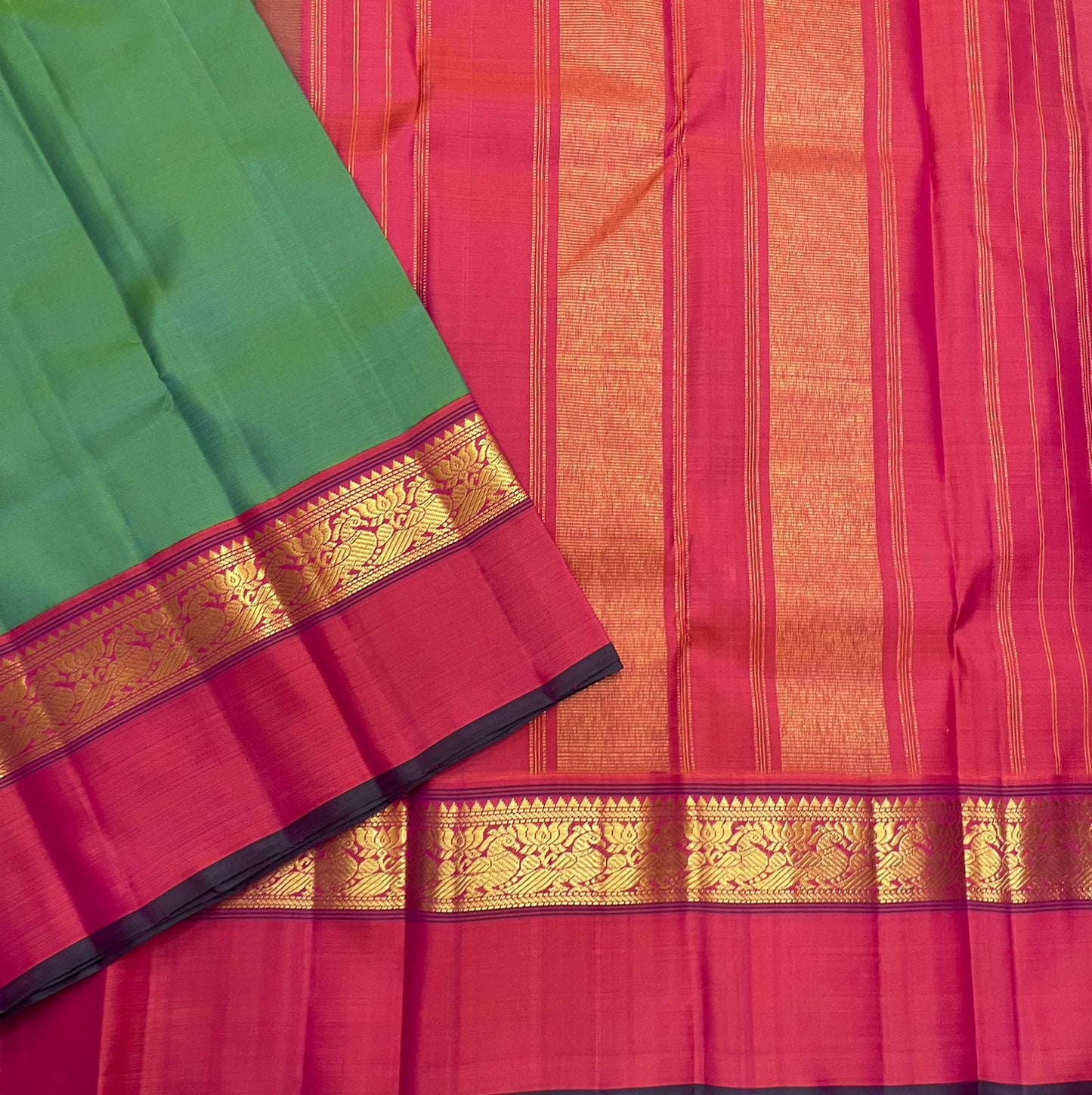 Green saree with pink border and gold zari woven band laid over a pink pallu with vertical zari stripes and gold panels.