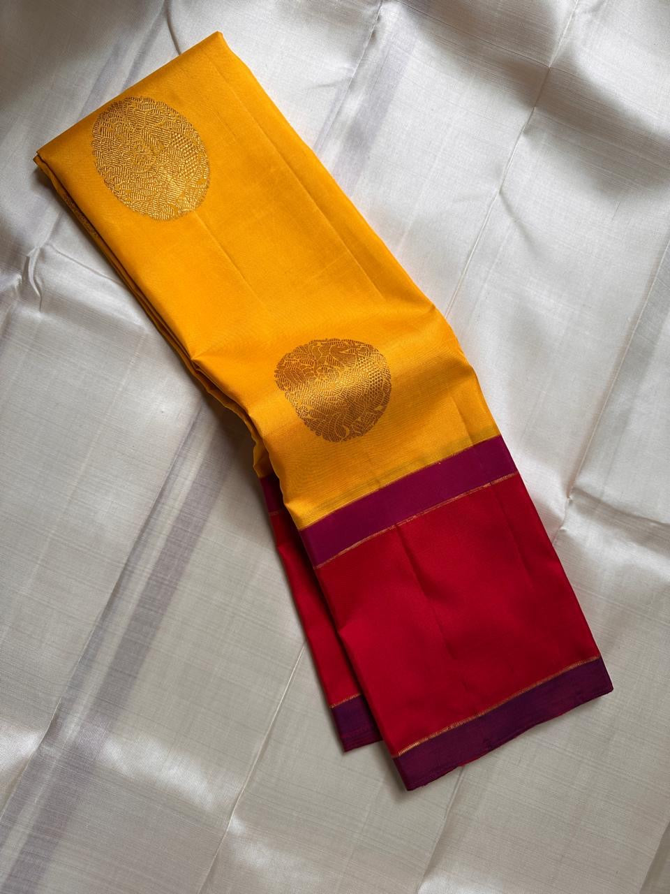Draped silk saree showing mustard yellow buttas, vermilion field and zari pallu details
