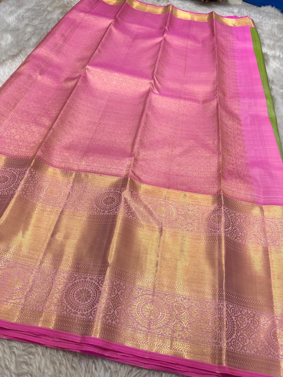 Full spread of pink zari woven pallu with ornate gold patterns and contrast green edge