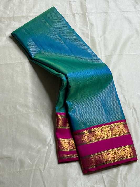 Kavi ✨ – Pure Kanchipuram Silk Saree
Teal Blue Silk Body with Lustrous Shot Weave
Rich Magenta Contrast Border in Gold Zari
Grand Pallu with Intricate Kili (Parrot) Motifs
Magenta Blouse with Matching Zari Border Silk Mark Certified, delivery in 2 weeks