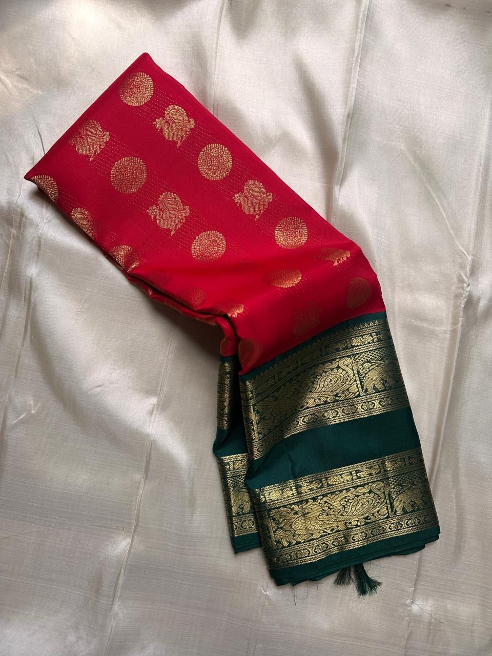 Sindoor red silk body with gold buttas and deep green elephant zari woven border close view