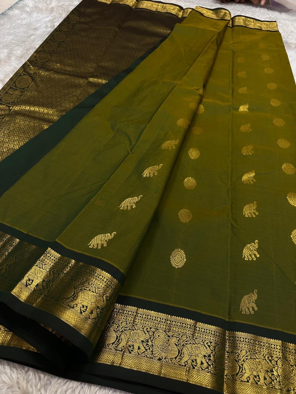 Olive Pachai – Pure Korvai Kanchipuram Silk Saree
Olive green body with gold zari gaja & medallion buttas
Contrast black korvai border with peacock & floral vines
Grand brocade pallu with lattice & temple patterns
Silk Mark Certified …chk description