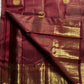 Pavila – Rich brown pure silk Kanchipuram saree in shimmering zari kattam checks. Layered varisaipet borders feature peacocks, yazhi, and rudraksham motifs in ornate zari. A bold broad yazhi adai motif lends ceremonial elegance. Grand  ornate Pallu