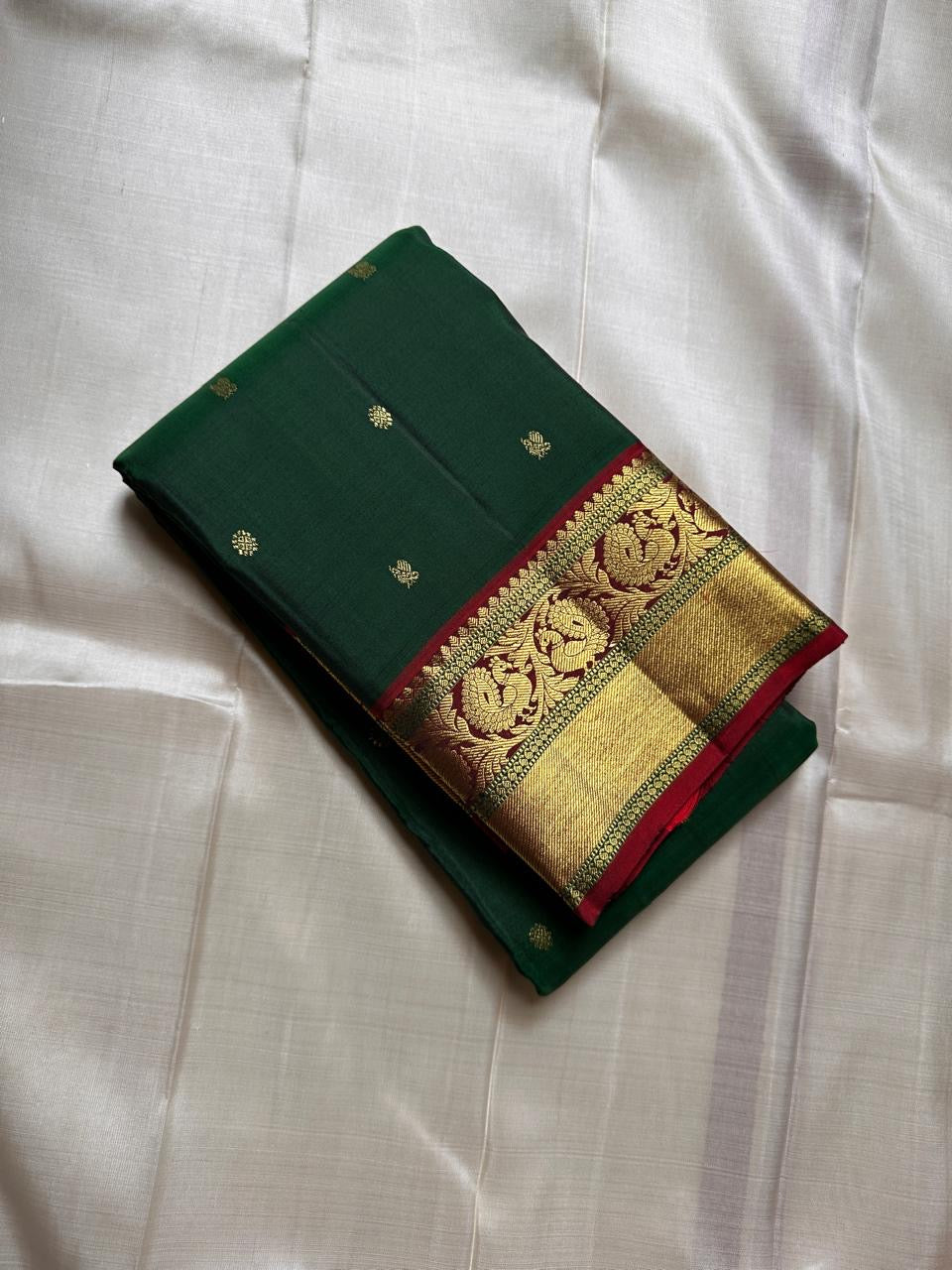 Emerald Glow ✨ – Pure Kanchipuram Silk Saree

Deep Green Body with Gold Floral Buttas

Maroon Korvai Border with Peacock & Floral Zari Motifs

Grand Gold Zari Brocade Pallu with Diamond Lattice Weave

Silk Mark Certified | Fall & Pico Done | Blouse Stitch