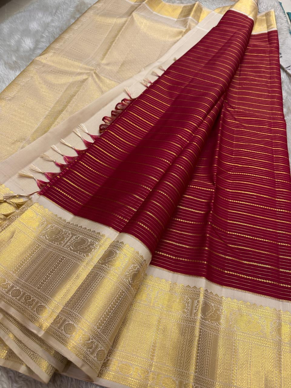 Full view of red striped Kanchipuram silk pallu with intricate gold zari and tassels