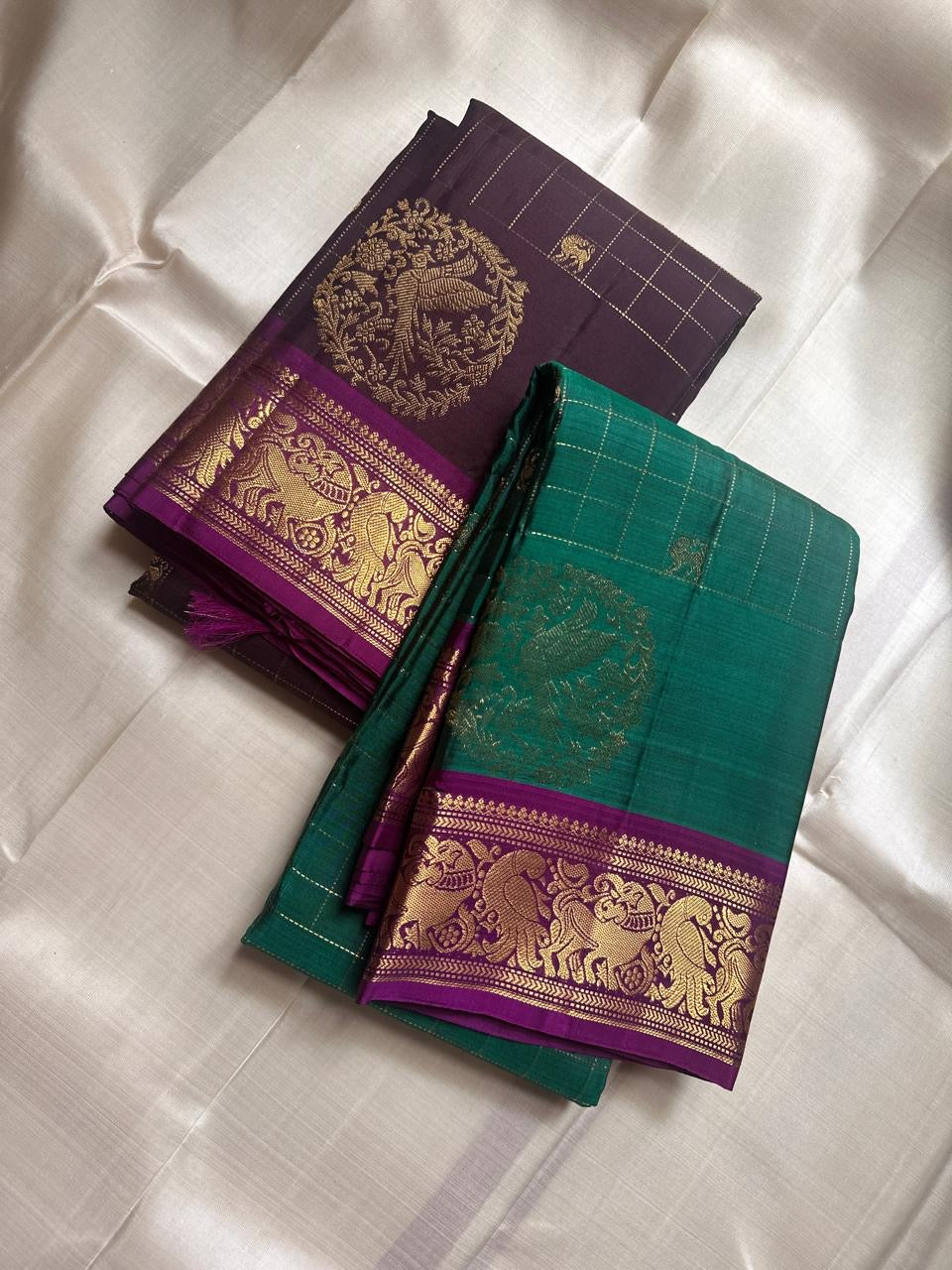 Sorgavaasal Kili – Pure Silk Kanchipuram Saree in Teal with Purple Zari Kattam
Intricately handwoven with traditional zari kattam checks and adorned with exquisite zari-woven Yazhi buttas, this saree features a vibrant teal body paired with a regal purple