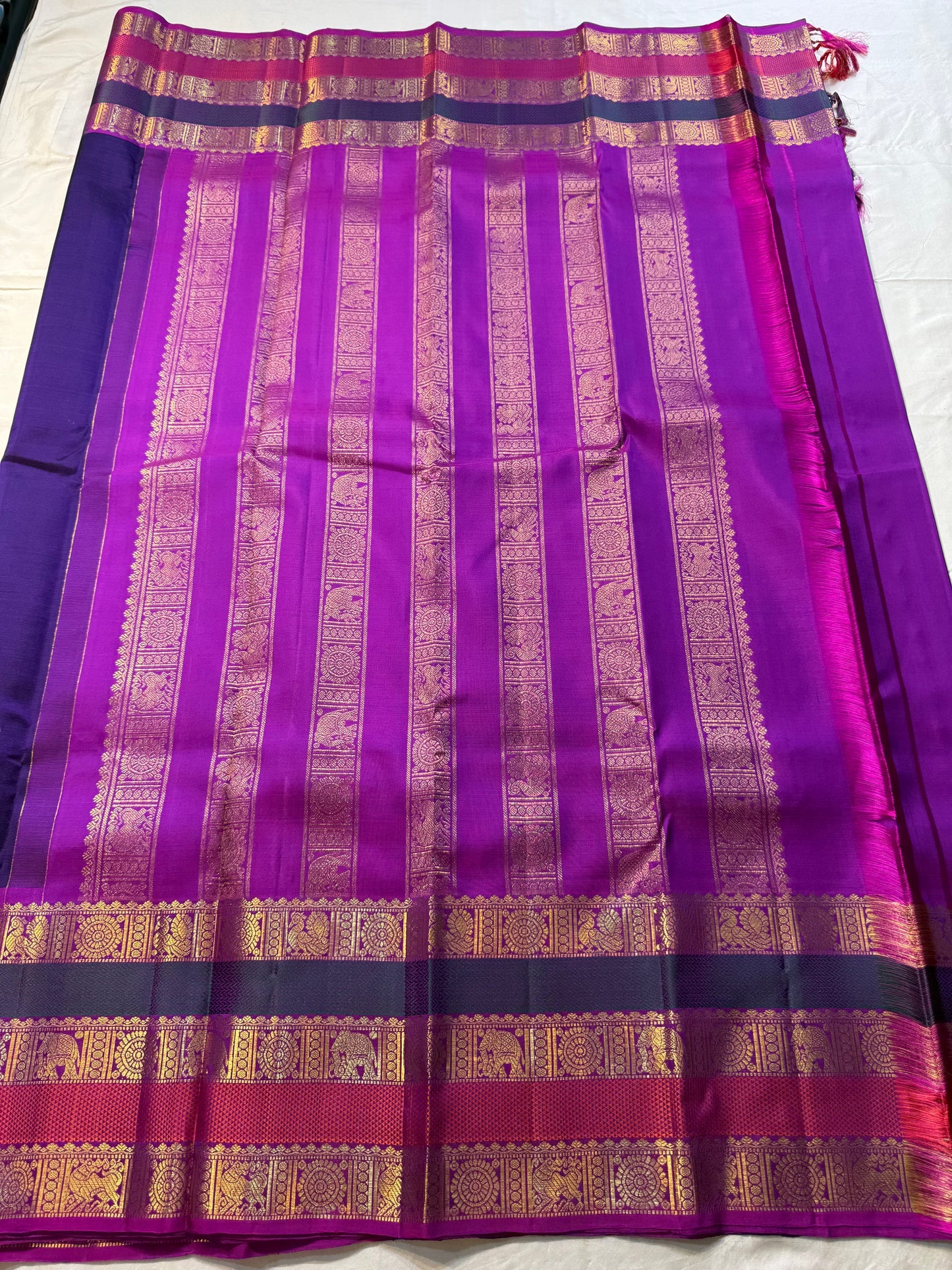 Peacock Purple Rajam – Pure Silk Kanchipuram Saree
Deep Peacock Purple Body with Gold Zari Buttas
Korvai Borders with Temple, Peacock & Elephant Motifs
Rich Zari Pallu with Vertical Brocade Stripes
Silk Mark Certified | ships in two week| Blouse Stitching